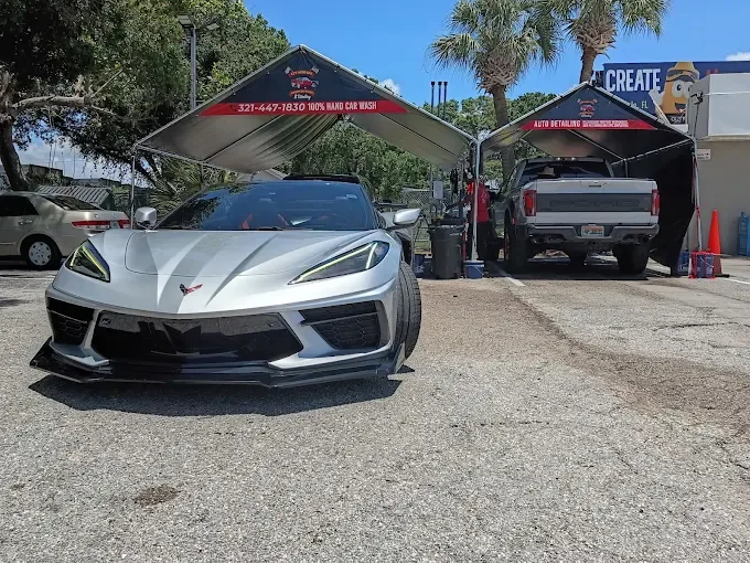 Silver Corvette and Ford Raptor under the AJS Auto Spa hand wash canopy