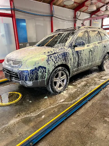 SUV covered in foam during hand wash at DLuxe Hand Car Wash bay