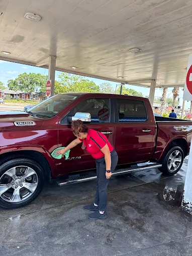 Staff member wiping down red Ram 1500 truck at Sparkling Image Car Wash